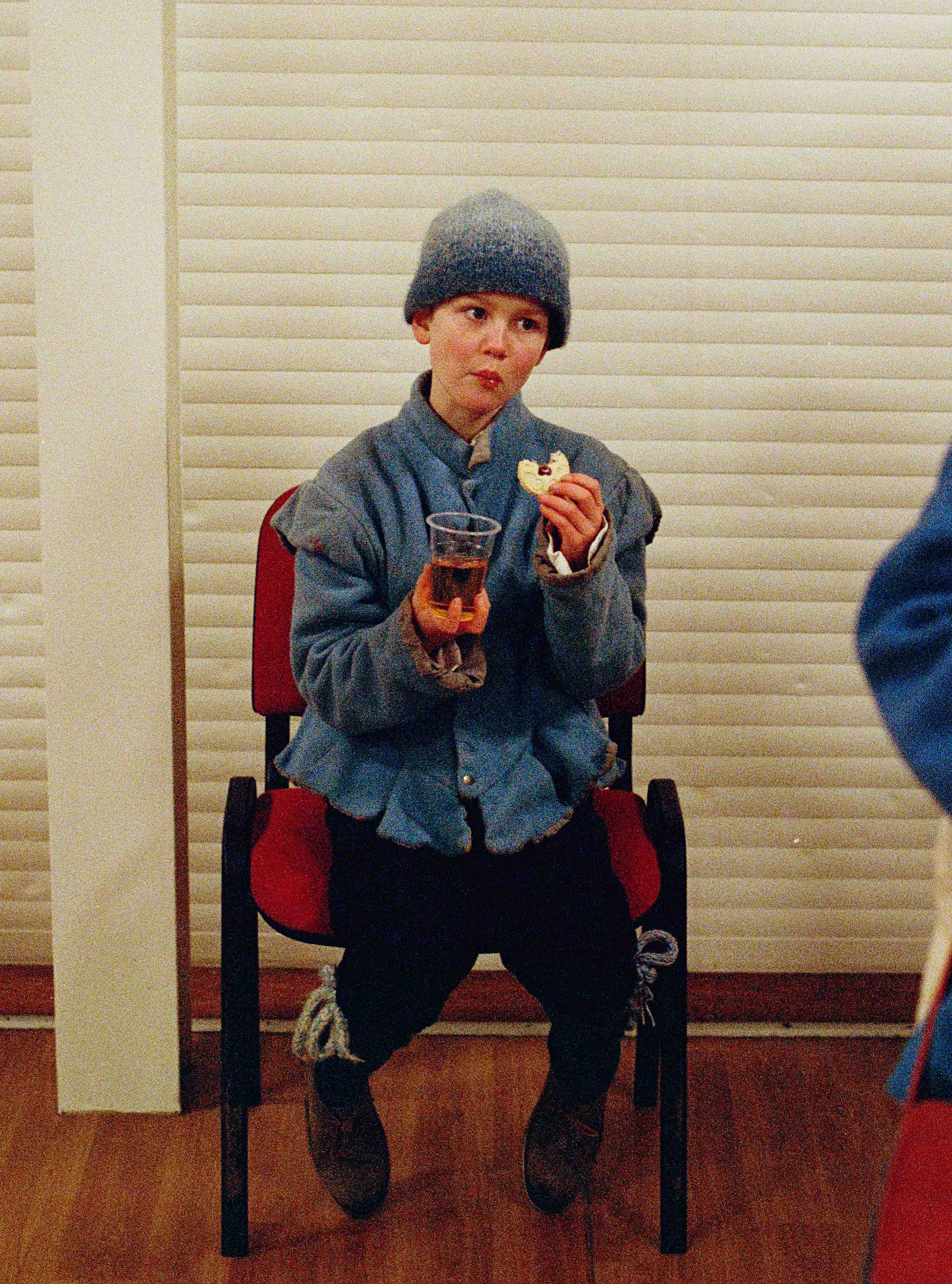 Young boy sat eating biscuit