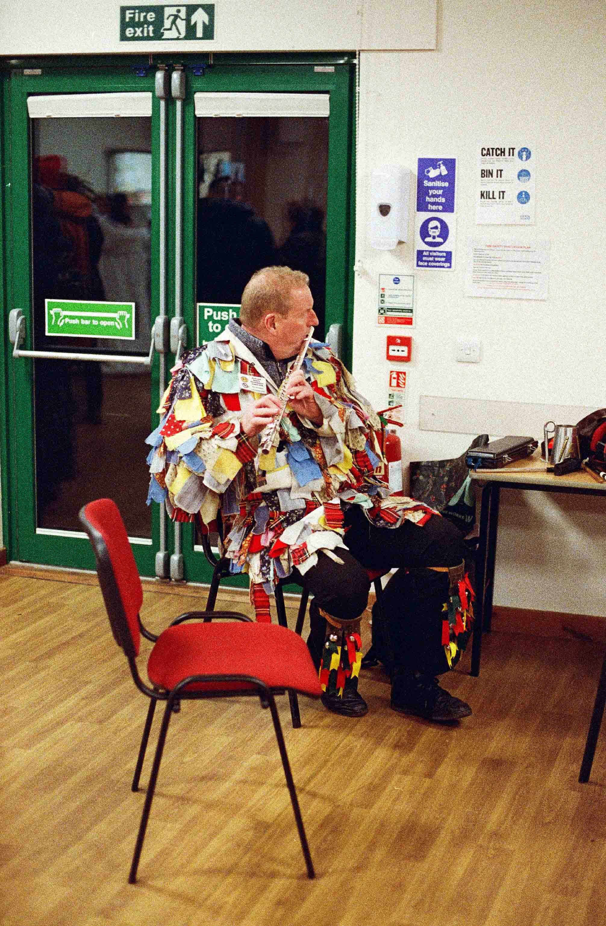 Rag coat morris man plays the flute inside in the light