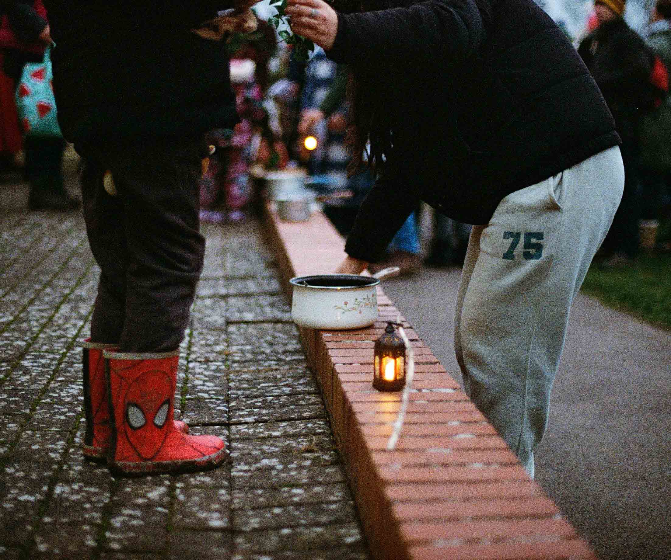 A mother helps her child above decorated enamel pot