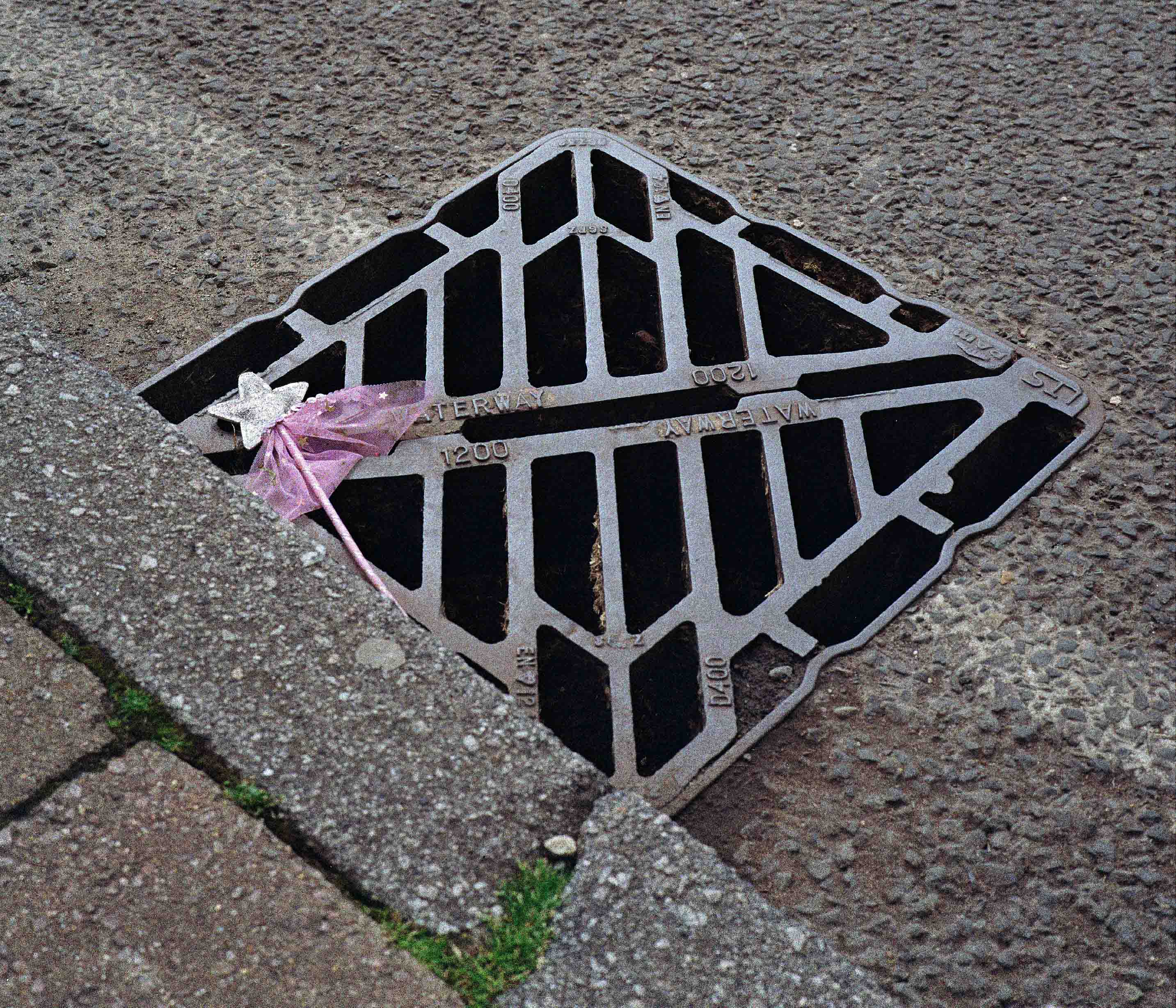 child's toy fairy wand lying on a drain cover